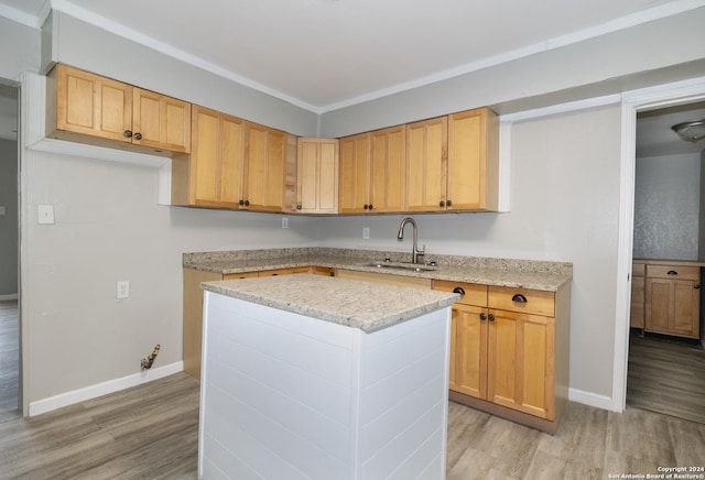 kitchen with light stone countertops, light brown cabinetry, sink, a center island, and light hardwood / wood-style floors