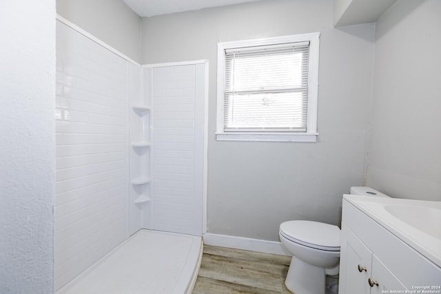 bathroom featuring a tile shower, vanity, hardwood / wood-style flooring, and toilet