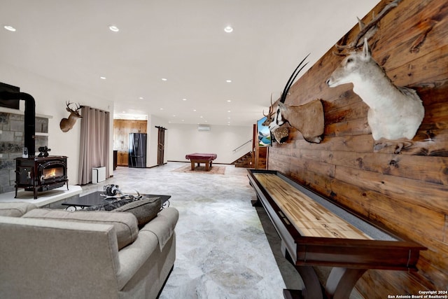 interior space featuring a wood stove, wood walls, and pool table
