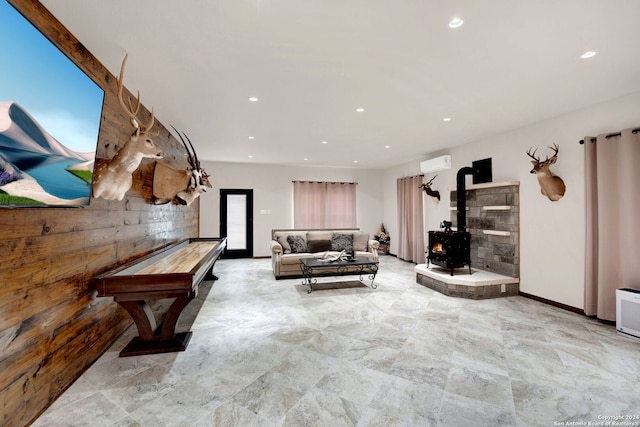 recreation room featuring a wood stove, wooden walls, and a wall unit AC