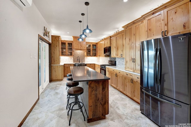 kitchen with stainless steel refrigerator, a center island, black gas range oven, a kitchen breakfast bar, and decorative light fixtures