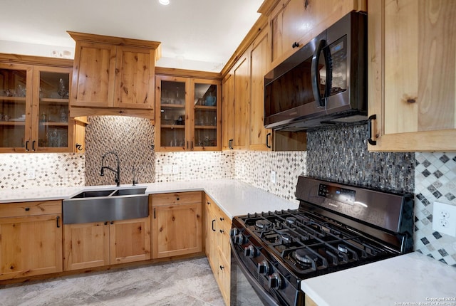 kitchen featuring black gas range oven, tasteful backsplash, and sink
