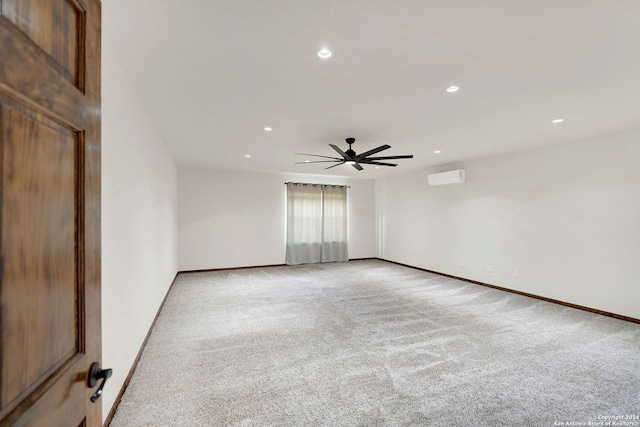 spare room featuring a wall unit AC, ceiling fan, and light colored carpet