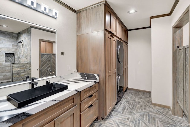 bathroom with a tile shower, vanity, and ornamental molding
