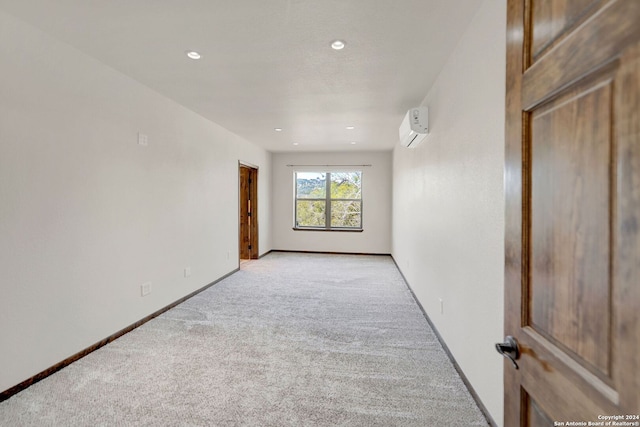 spare room featuring a wall mounted air conditioner and light carpet