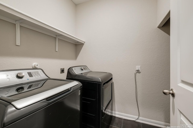 laundry room with washing machine and clothes dryer and dark tile patterned floors