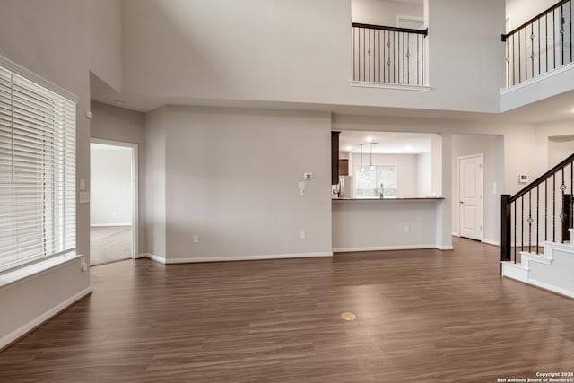 unfurnished living room with dark hardwood / wood-style floors, plenty of natural light, and a high ceiling