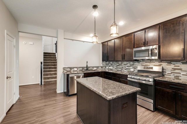 kitchen with dark brown cabinetry, light stone countertops, a center island, and appliances with stainless steel finishes