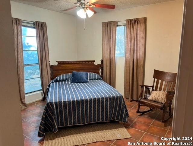 bedroom featuring a textured ceiling, tile patterned floors, and ceiling fan