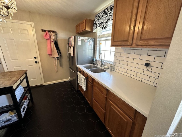 kitchen with stainless steel refrigerator, sink, tasteful backsplash, dark tile patterned floors, and a textured ceiling