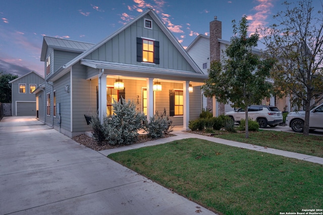 view of front of home featuring a lawn, a garage, and covered porch