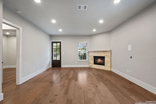 unfurnished living room featuring light wood-type flooring and a stone fireplace