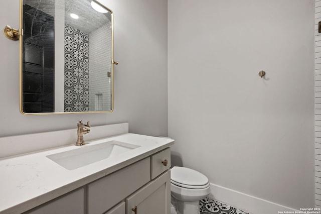 bathroom with tile patterned floors, vanity, a tile shower, and toilet