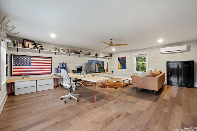 office space featuring ceiling fan, light hardwood / wood-style floors, and a wall unit AC