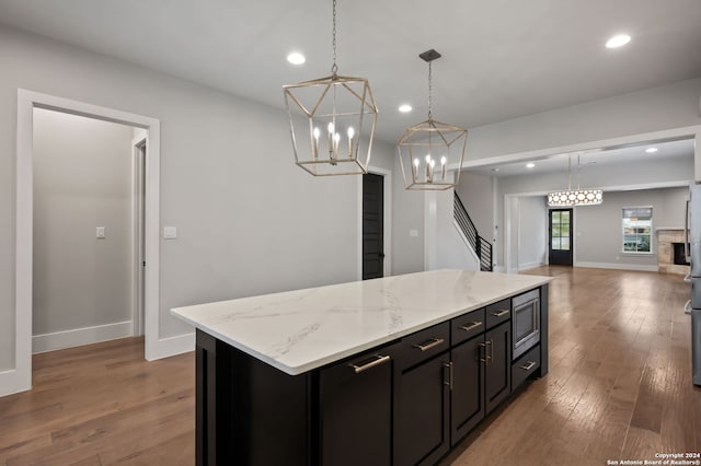 kitchen featuring pendant lighting, a center island, stainless steel microwave, and hardwood / wood-style flooring