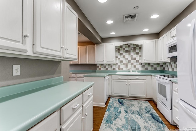 kitchen featuring tasteful backsplash, white appliances, dark wood-type flooring, sink, and white cabinetry