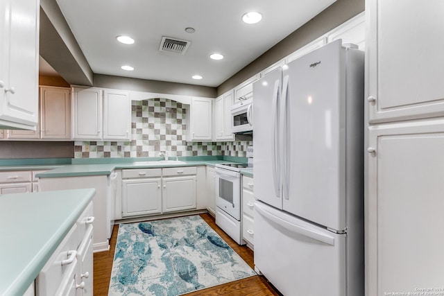 kitchen featuring white cabinetry, sink, dark hardwood / wood-style flooring, white appliances, and decorative backsplash