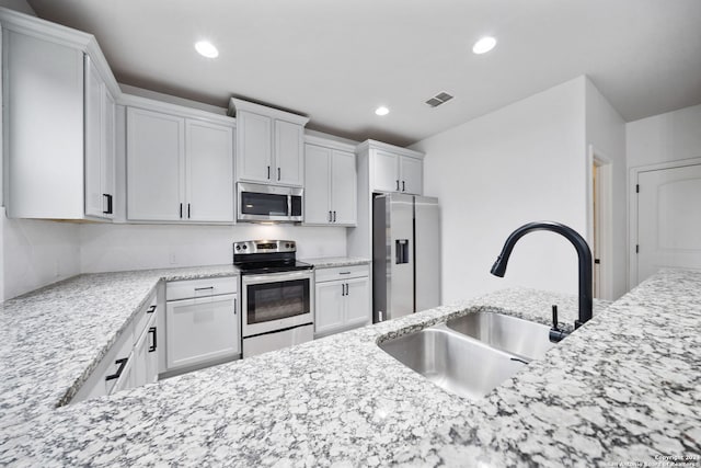 kitchen with light stone countertops, sink, white cabinets, and stainless steel appliances