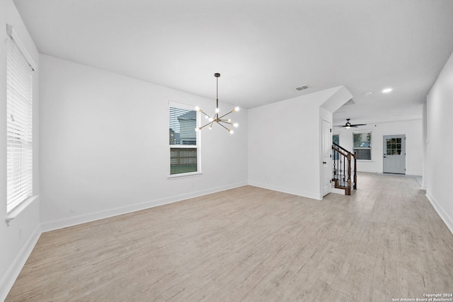 unfurnished living room featuring ceiling fan with notable chandelier and light hardwood / wood-style floors