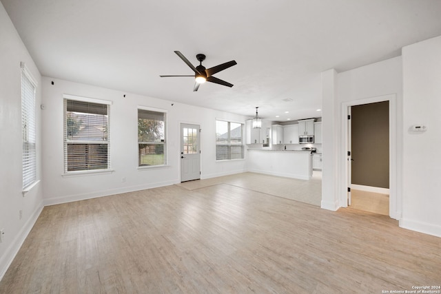 unfurnished living room featuring light hardwood / wood-style floors and ceiling fan with notable chandelier