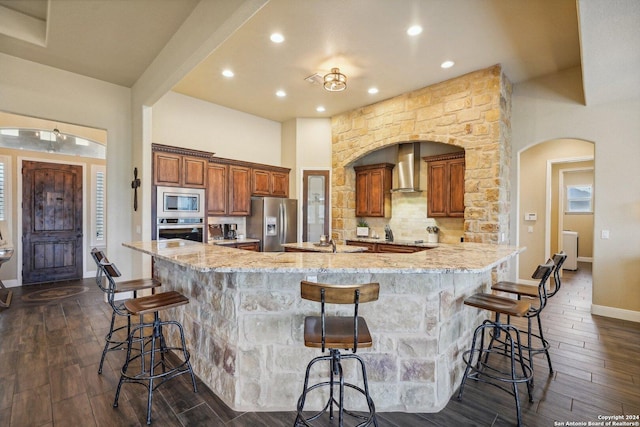 kitchen featuring appliances with stainless steel finishes, light stone counters, a spacious island, dark hardwood / wood-style floors, and a breakfast bar area