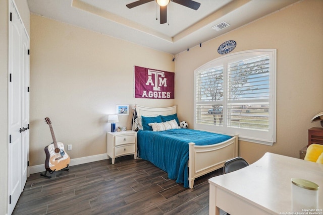 bedroom with dark hardwood / wood-style floors, a raised ceiling, and ceiling fan