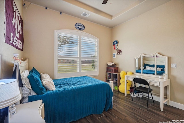 bedroom featuring dark hardwood / wood-style floors, a raised ceiling, and ceiling fan