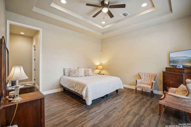 bedroom featuring a raised ceiling, ceiling fan, and dark hardwood / wood-style flooring