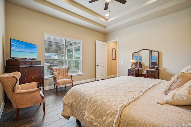 bedroom with a tray ceiling, ceiling fan, and dark hardwood / wood-style floors