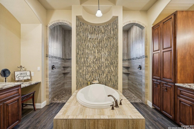 bathroom with hardwood / wood-style flooring, vanity, and shower with separate bathtub