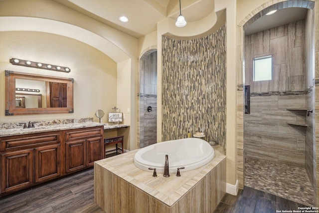 bathroom featuring hardwood / wood-style flooring, vanity, and plus walk in shower