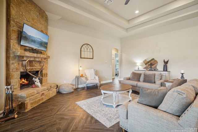 living room featuring dark parquet floors, ceiling fan, and a fireplace