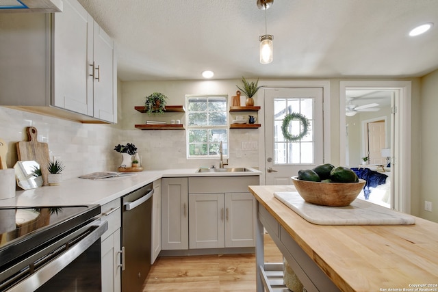 kitchen featuring wood counters, backsplash, stainless steel appliances, sink, and light hardwood / wood-style flooring