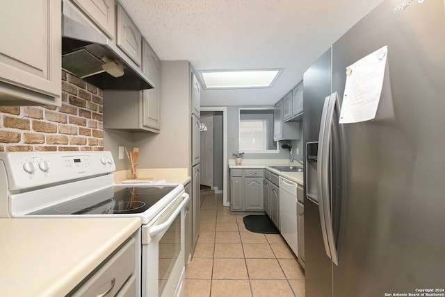 kitchen featuring a textured ceiling, gray cabinetry, light tile patterned floors, and white appliances