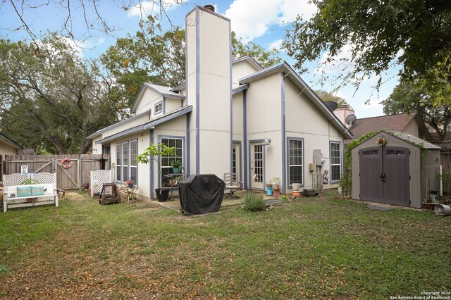 rear view of property with a lawn, a storage shed, and a patio