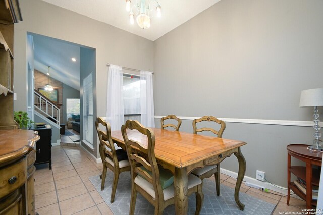 dining area featuring light tile patterned floors, ceiling fan with notable chandelier, and vaulted ceiling