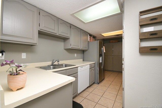 kitchen with gray cabinetry, dishwasher, sink, and stainless steel refrigerator with ice dispenser