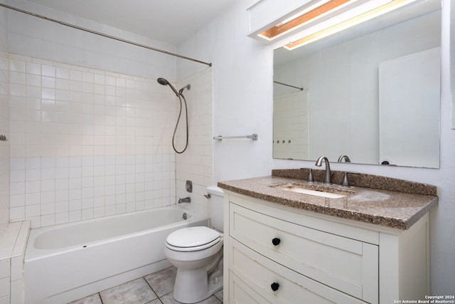 full bathroom with vanity, tiled shower / bath, a skylight, tile patterned flooring, and toilet