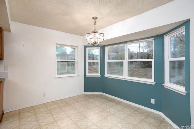 unfurnished dining area featuring a chandelier and a textured ceiling