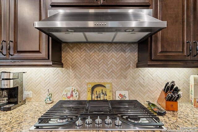 kitchen featuring stainless steel gas cooktop, dark brown cabinetry, extractor fan, and tasteful backsplash