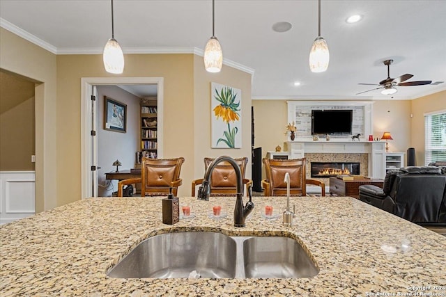 kitchen featuring light stone counters, sink, ceiling fan, and ornamental molding