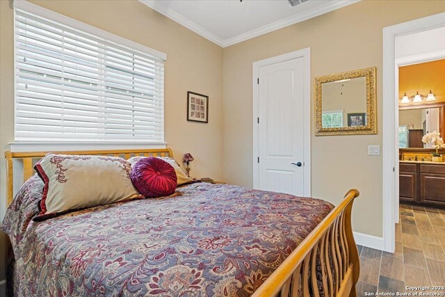 bedroom with light wood-type flooring, crown molding, and connected bathroom