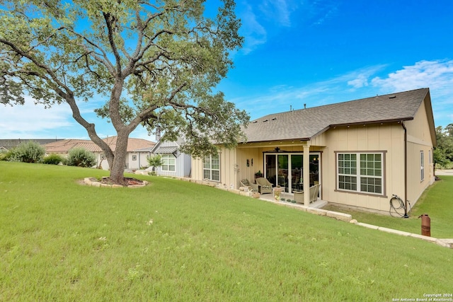 rear view of property featuring ceiling fan, a patio area, and a yard