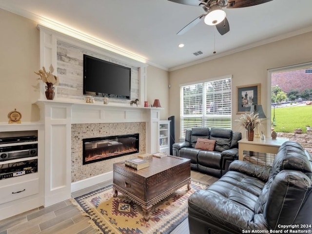 living room featuring a tile fireplace, crown molding, ceiling fan, and light hardwood / wood-style floors