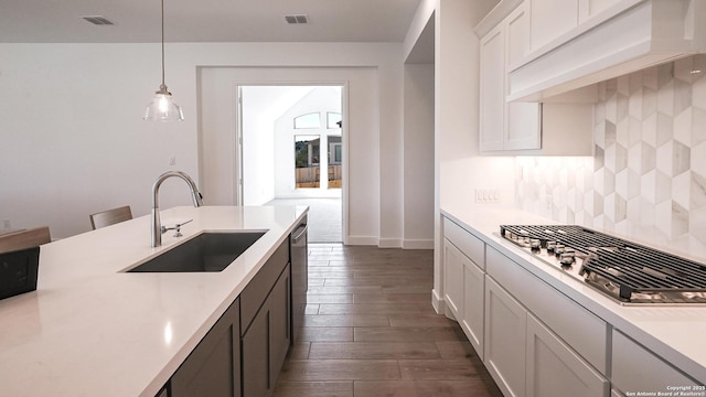 kitchen with custom exhaust hood, stainless steel appliances, tasteful backsplash, light countertops, and a sink