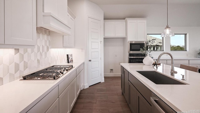 kitchen featuring stainless steel appliances, light countertops, backsplash, white cabinets, and a sink