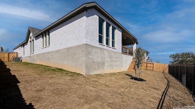 view of side of property featuring stairs, central AC, and fence