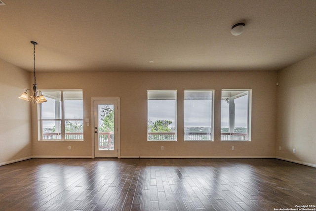 empty room with dark hardwood / wood-style flooring and a chandelier