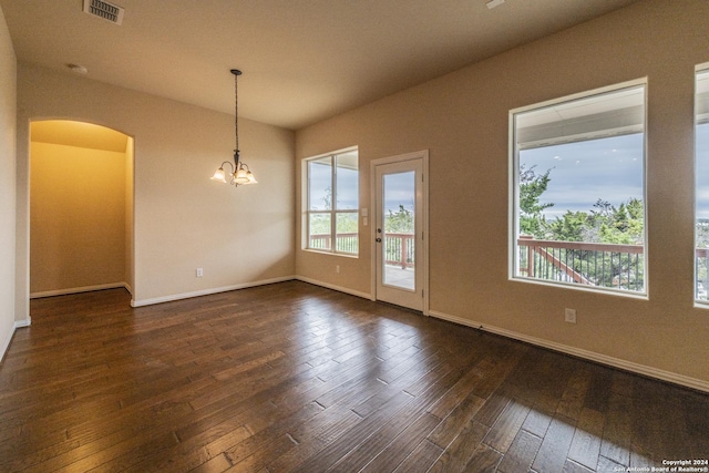 empty room with a notable chandelier and dark hardwood / wood-style flooring