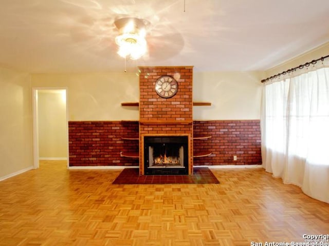 unfurnished living room featuring a brick fireplace, ceiling fan, brick wall, and light parquet floors